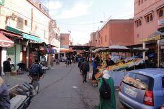 Busy Market Street in Marrakesh Medina with Fruit Stalls, Pedestrians, and Traditional Daily Life
