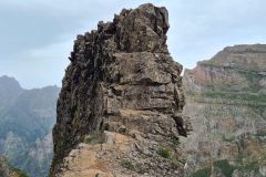 Narrow ridge passage beside jagged rock spine on PR1 Vereda do Areeiro, Madeira, Portugal