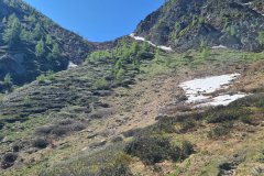 Late Spring Snow Patches on a Steep Alpine Slope Below Rocky Peaks