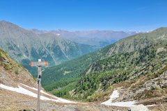 Mountain Pass Trail Sign Overlooking a High Alpine Valley in the Western Alps
