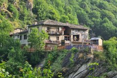 Cliffside Alpine Homes Overlooking a Forested Mountain Valley