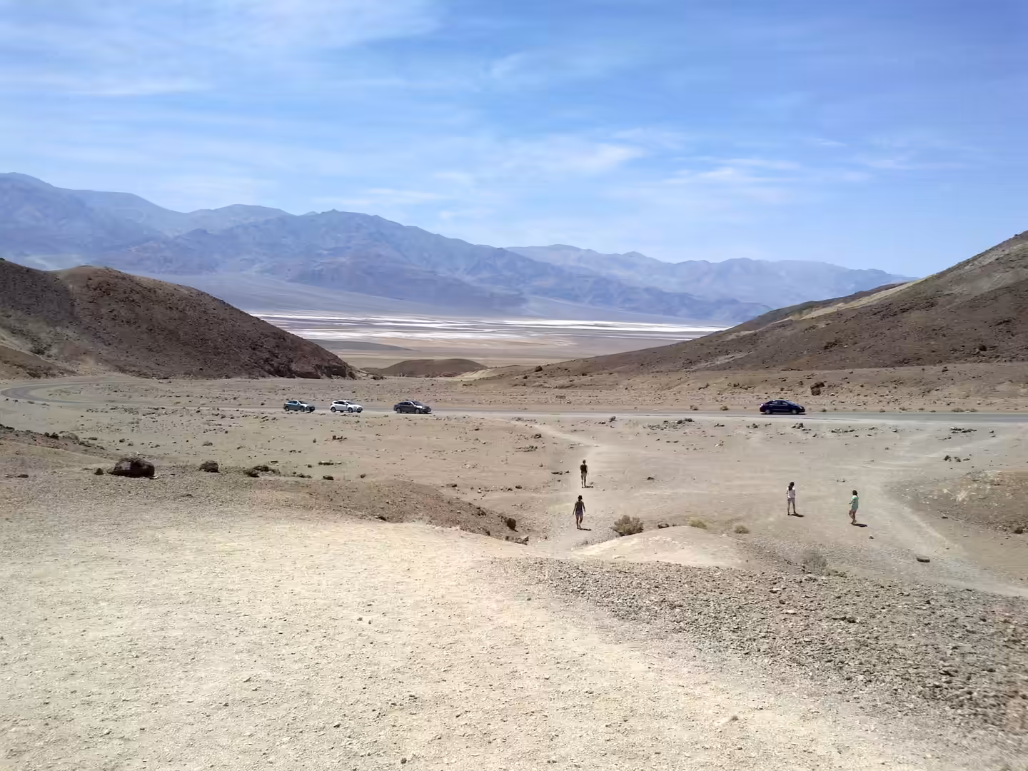 Visitors walking near a desert road overlooking Badwater Basin in Death Valley National Park