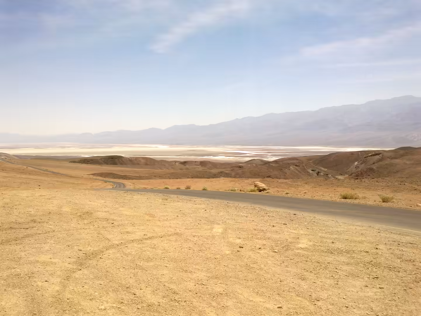 A winding desert road descending toward Badwater Basin in Death Valley National Park