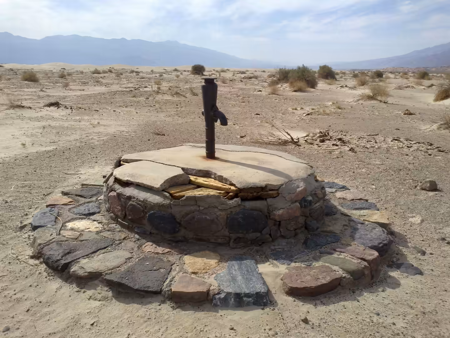 Historic hand pump over a stone-lined well in Death Valley National Park