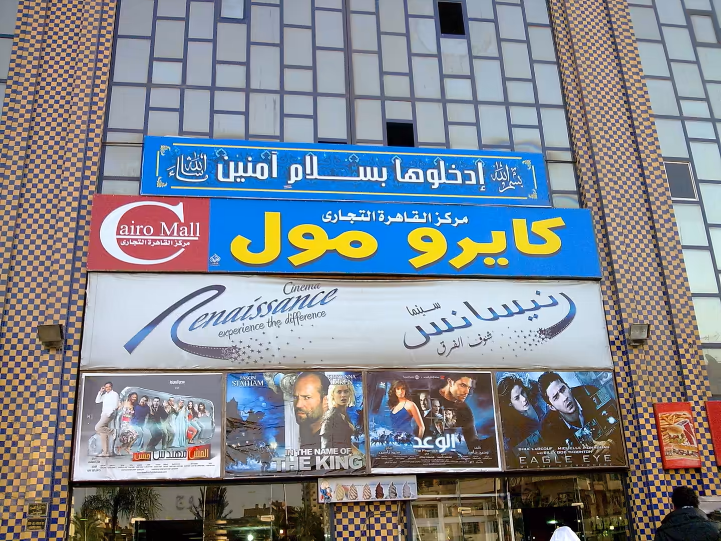 Mall and cinema entrance with Arabic signage and movie posters.