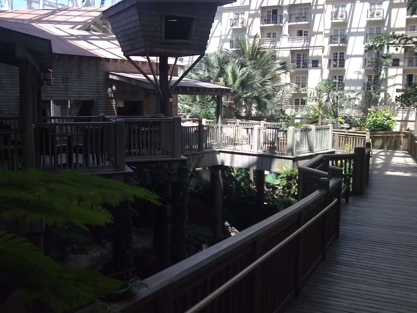 Indoor wooden boardwalk and dining area at Gaylord Palms near Orlando, surrounded by palms and a glass atrium.