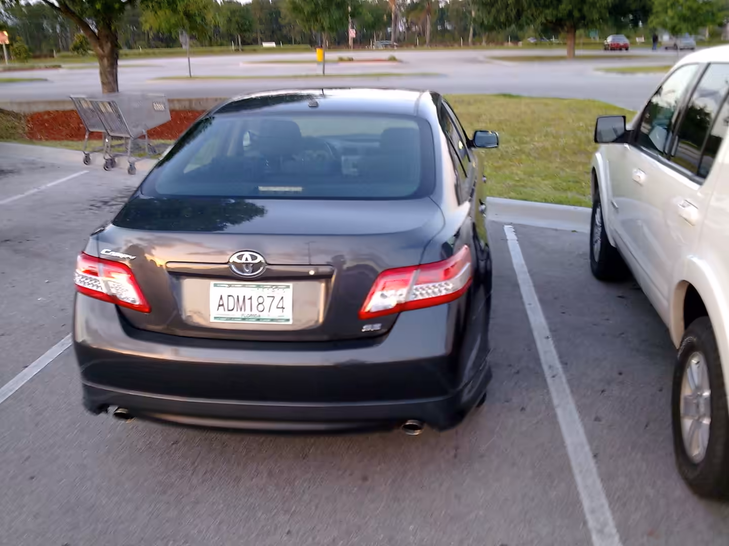 Dark gray sedan with Florida license plate parked in a lot beside an SUV.