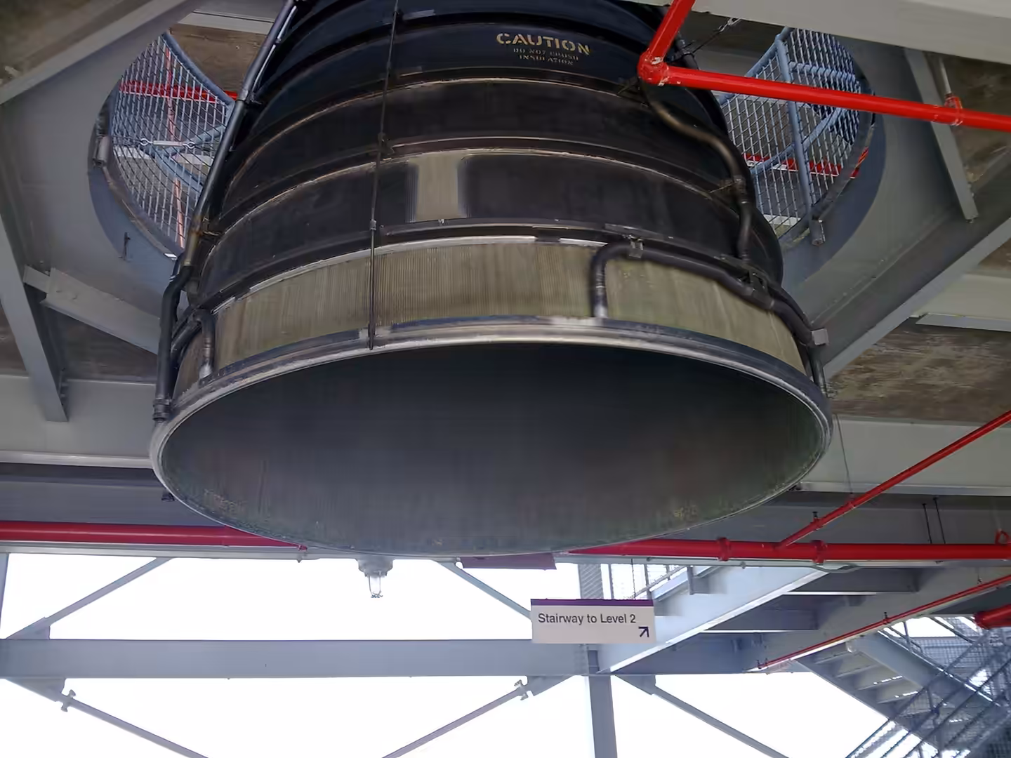 Close-up view of a large rocket engine nozzle suspended indoors at a space museum in Florida.