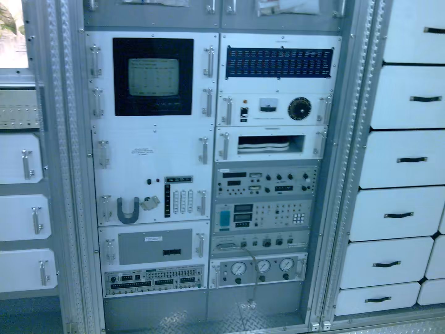 Vintage NASA equipment racks with gauges, switches, and monitoring displays.