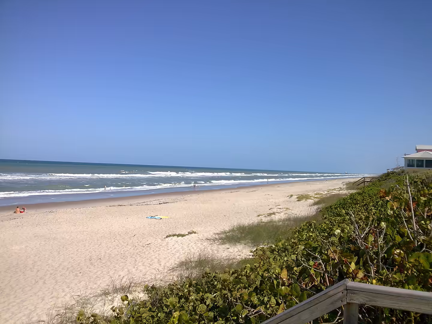 A wide sandy beach with gentle ocean waves under a clear blue sky in Florida.