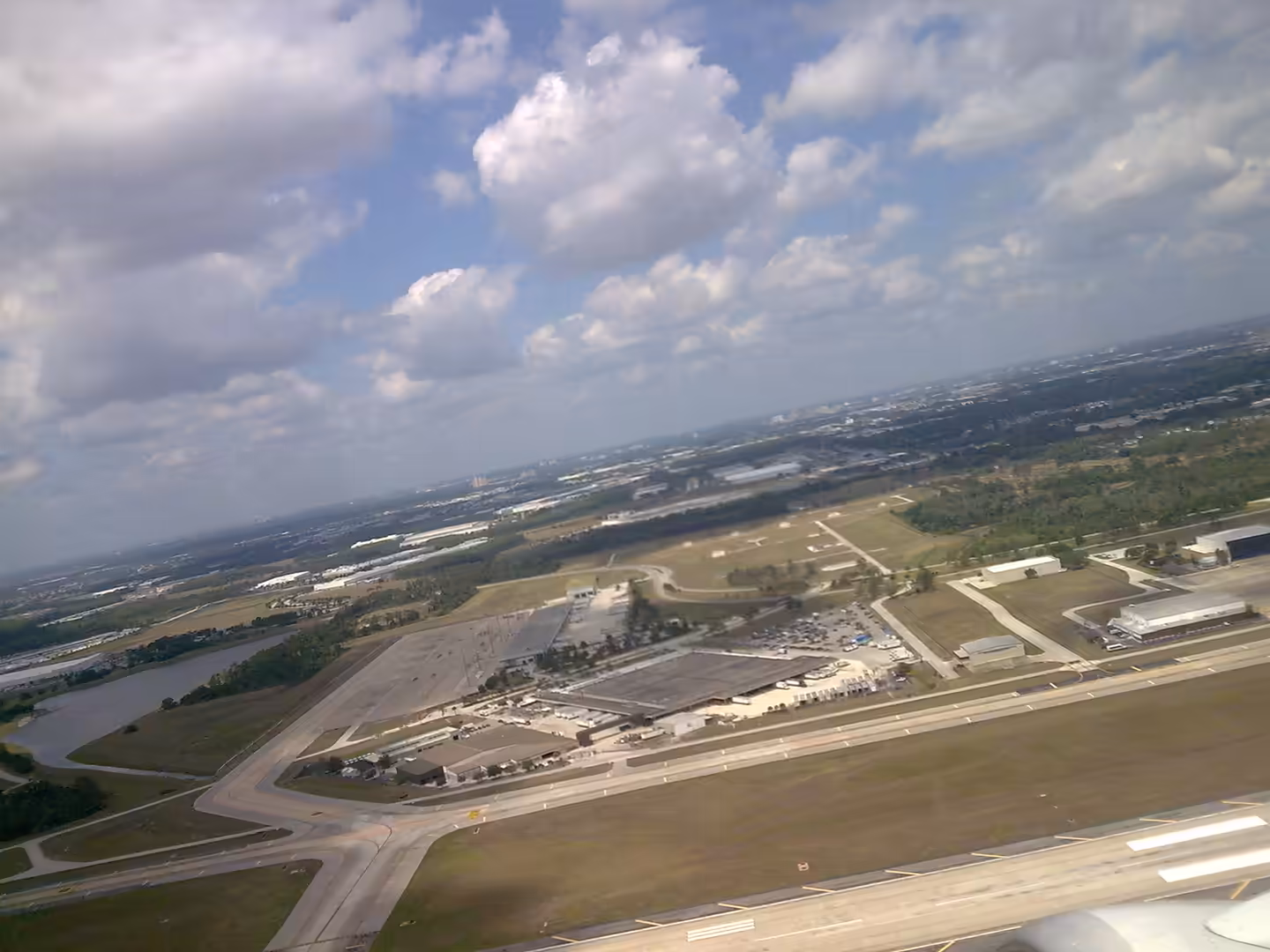 Aerial view of Orlando International Airport runways and surrounding landscape seen from an aircraft during takeoff.