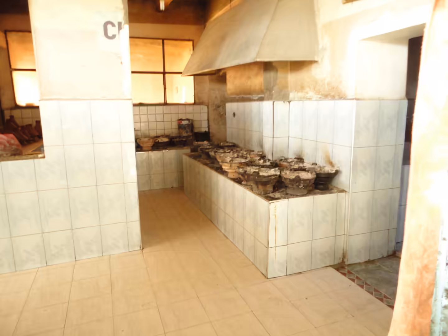 Interior of a traditional communal oven with tiled counters and rows of clay baking molds in Ouarzazate.