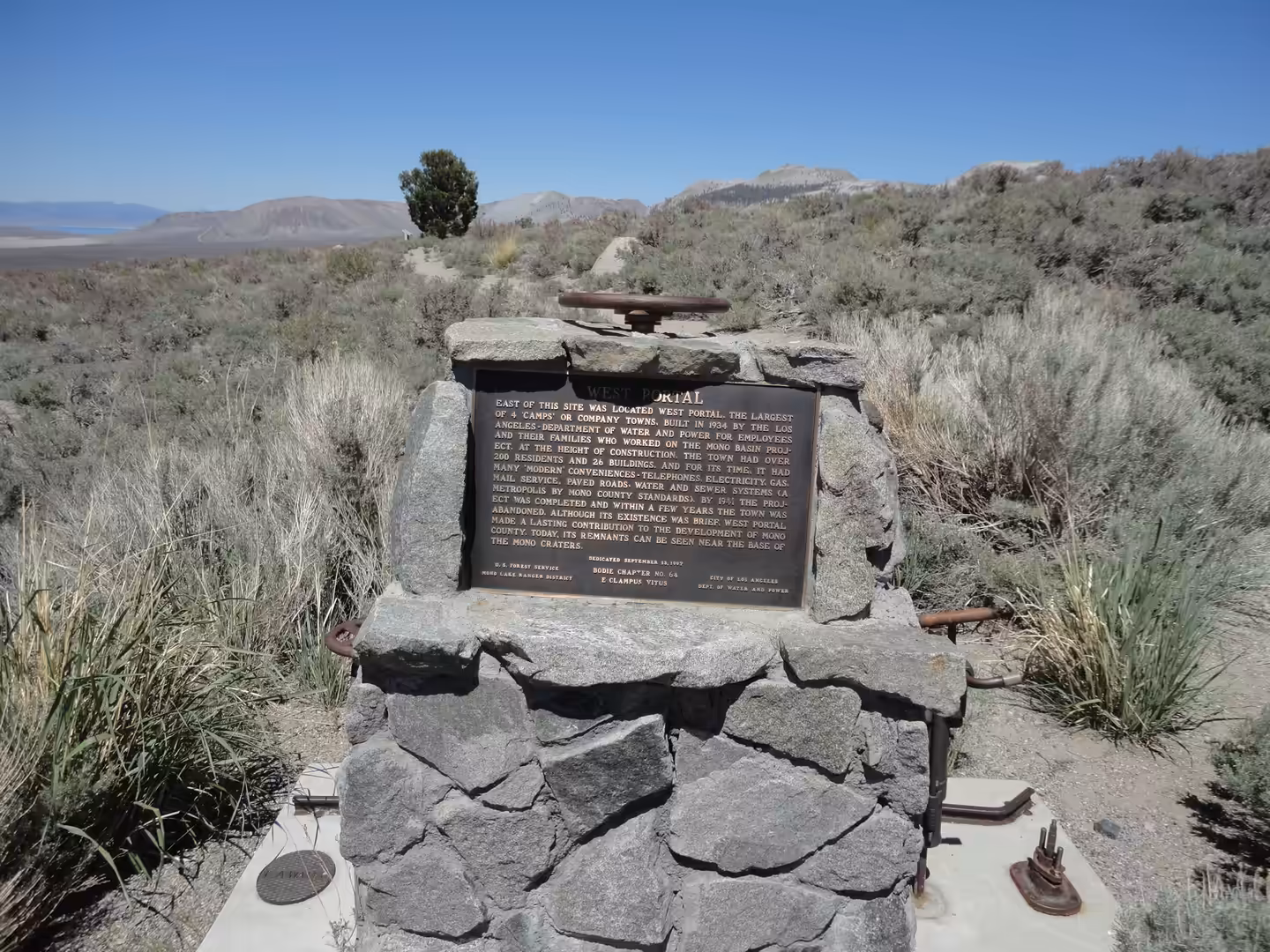 Stone monument with historical plaque set in sagebrush desert landscape