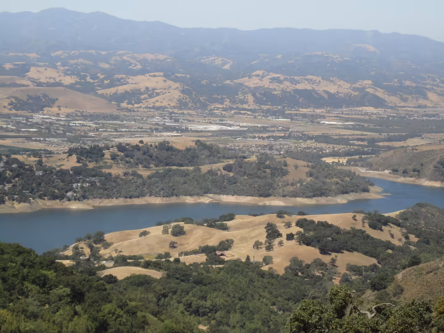 River-like reservoir winding through golden hills and farmland