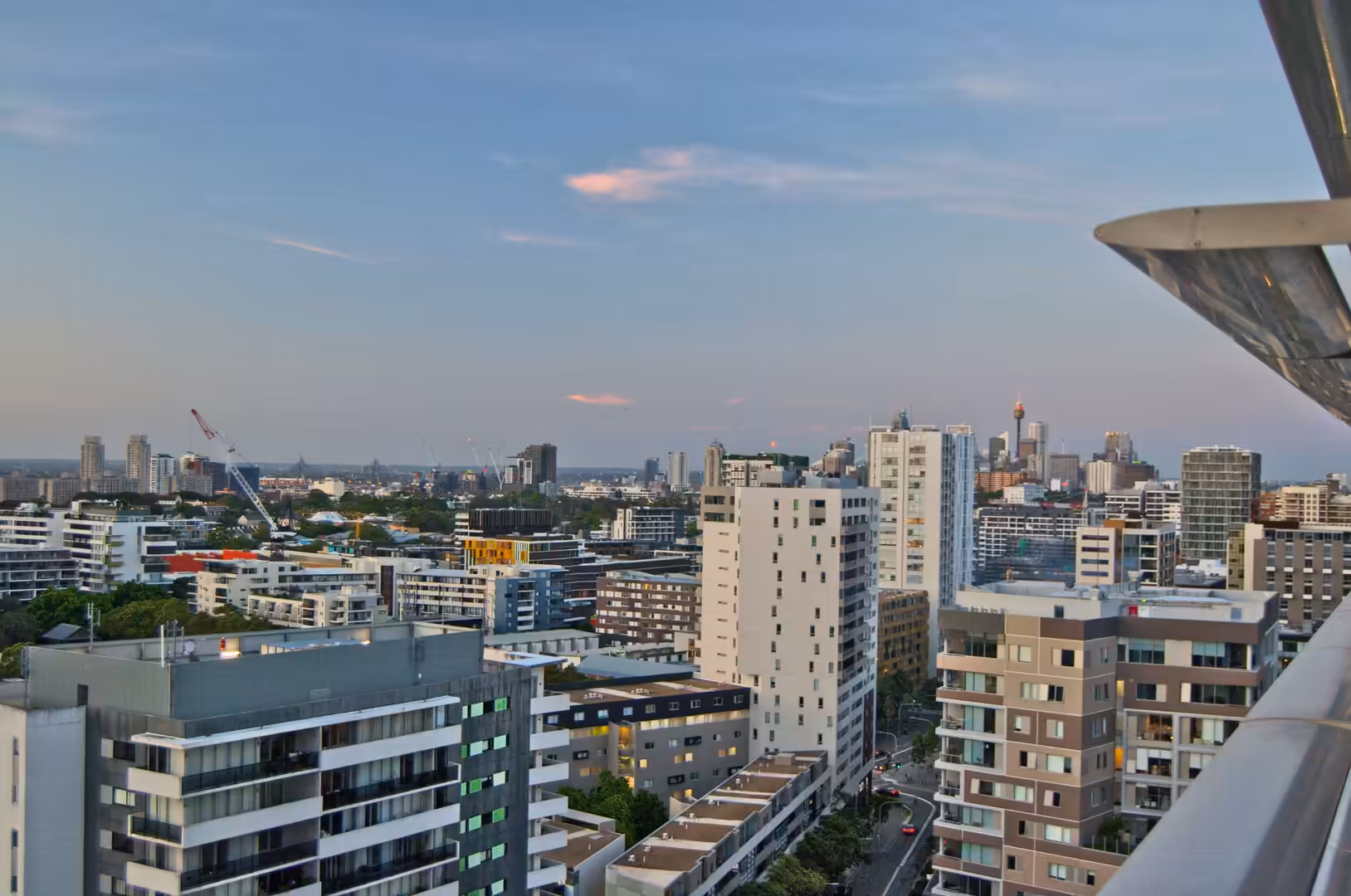 Evening skyline view from a high-rise balcony with a prominent observation tower.