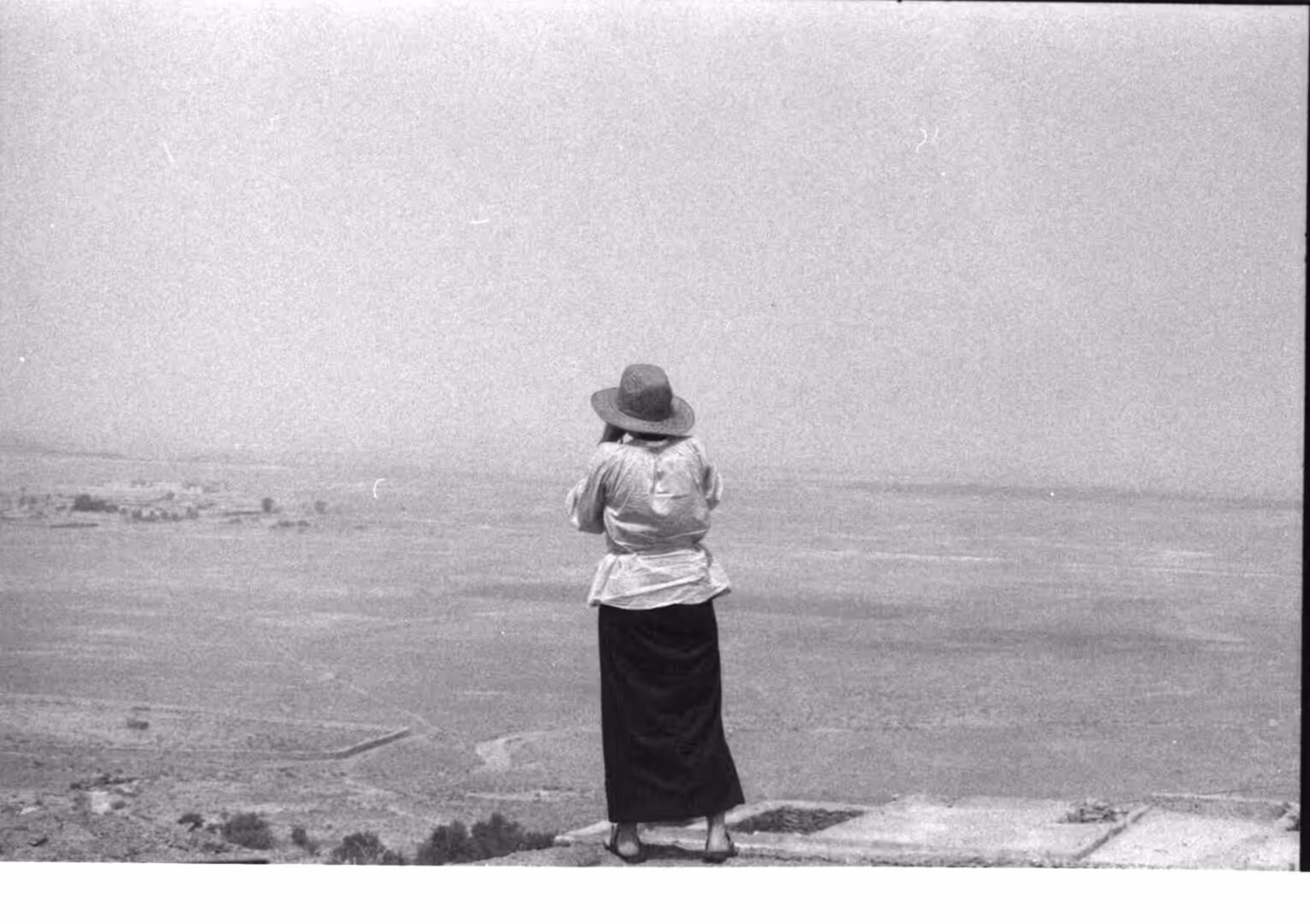 Person wearing a wide hat looking over a vast desert landscape in Morocco
