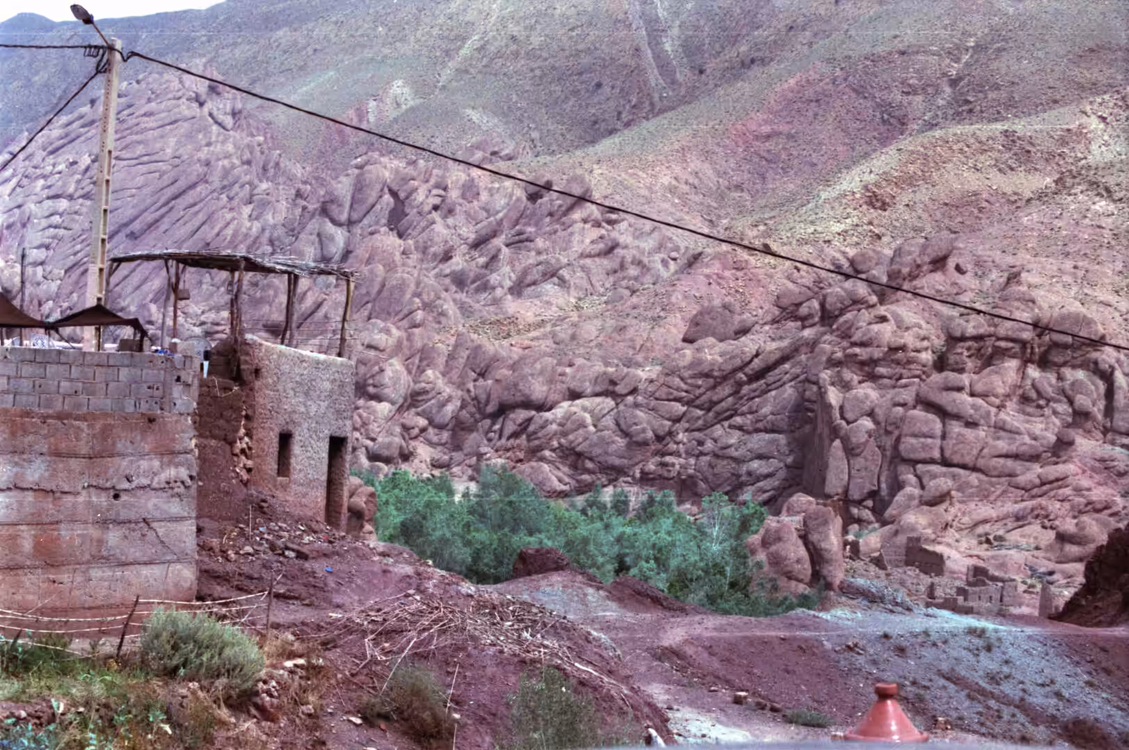 Mud-brick house beside rocky valley with green trees below
