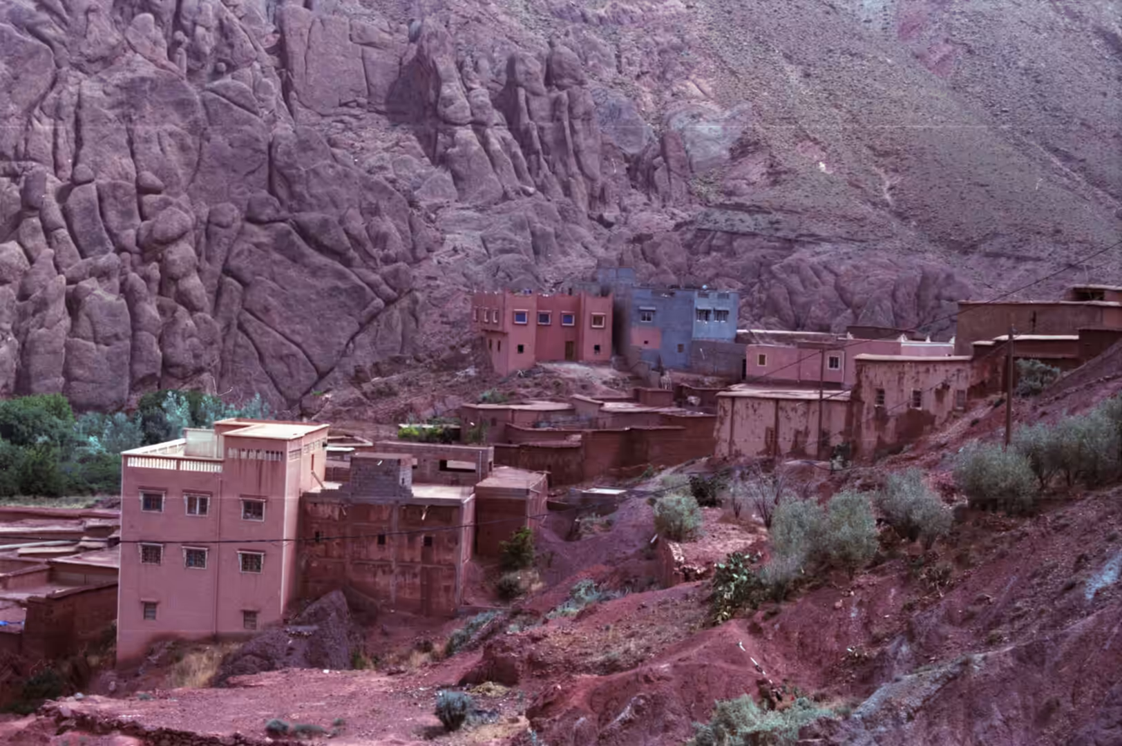 Village houses built against steep rocky cliffs in a desert mountain valley