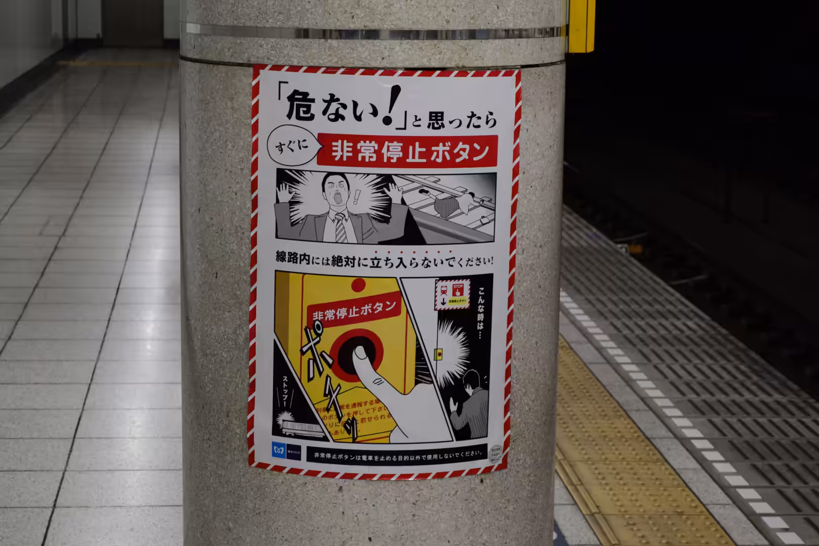 A comic-style poster on a subway pillar warns riders to press the emergency stop button, showing a shouting man beside a red button.