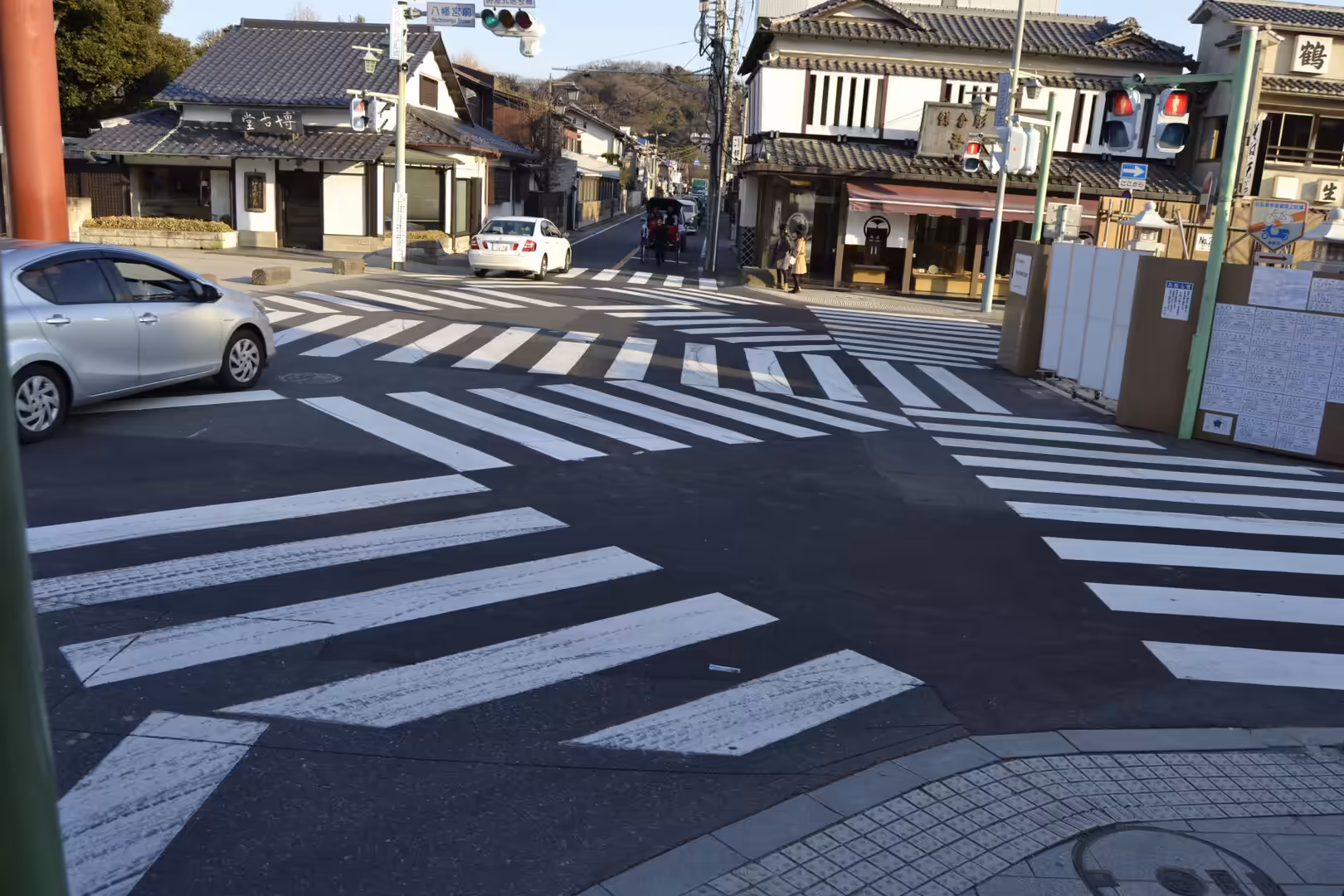 A scramble crossing with zebra stripes in every direction lies before traditional Japanese shopfronts.