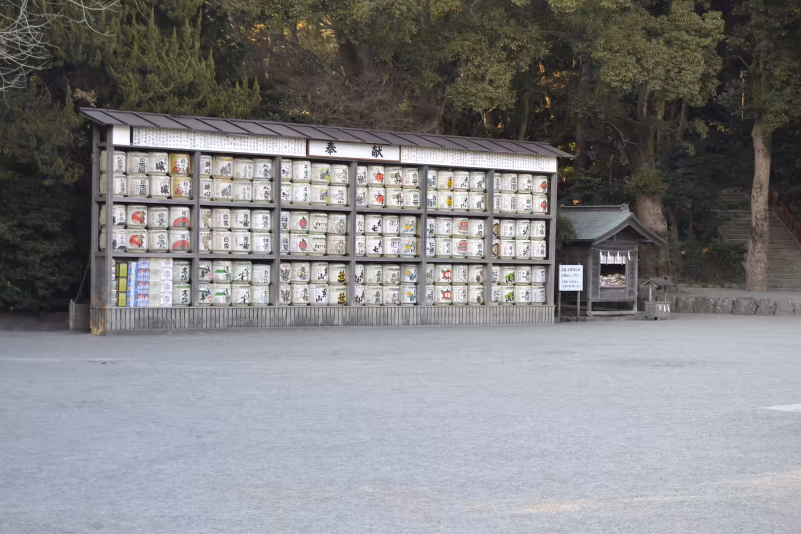 A wooden rack stacked with decorated sake barrels stands before a shrine in Kamakura.