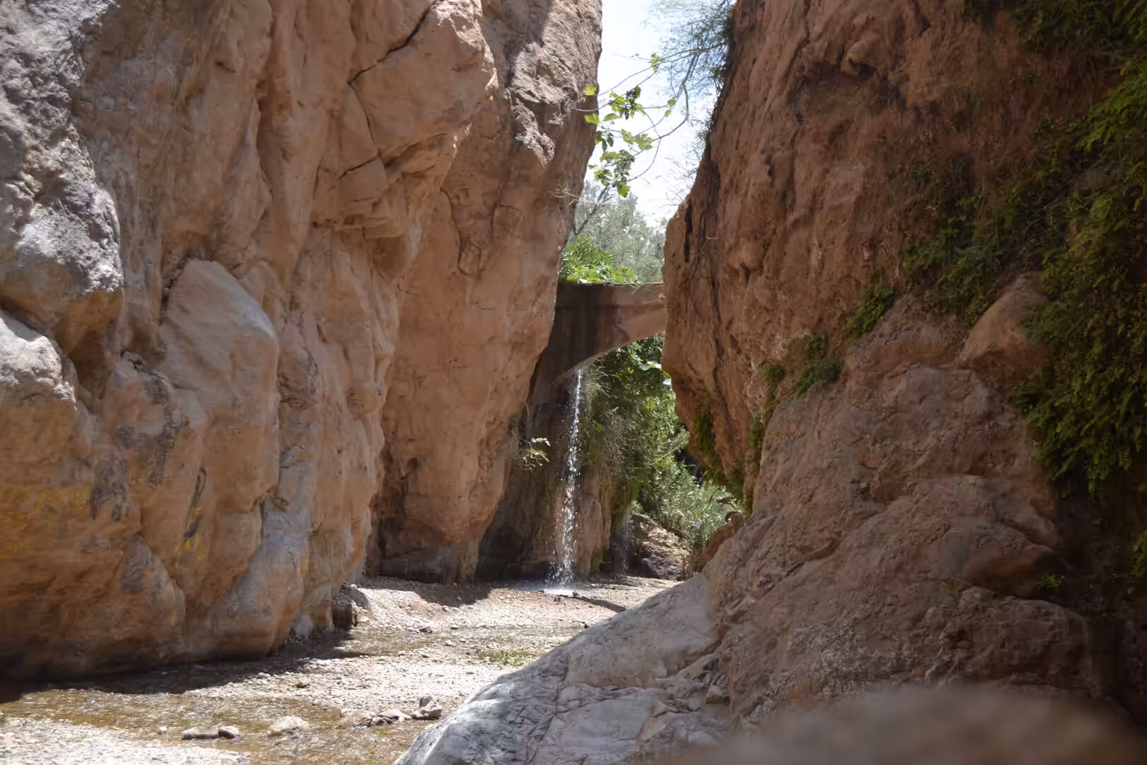 Small waterfall beneath a stone bridge in a narrow canyon