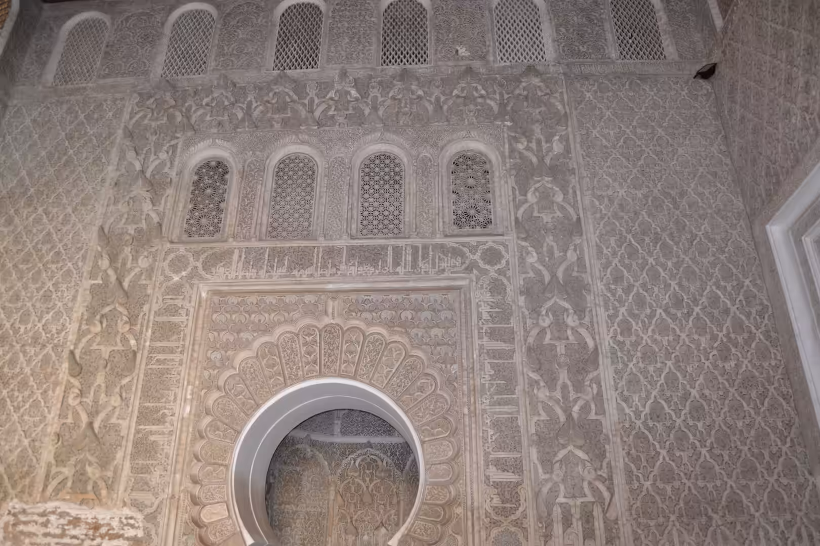 Intricate carved stucco wall and arch inside Ben Youssef Madrasa