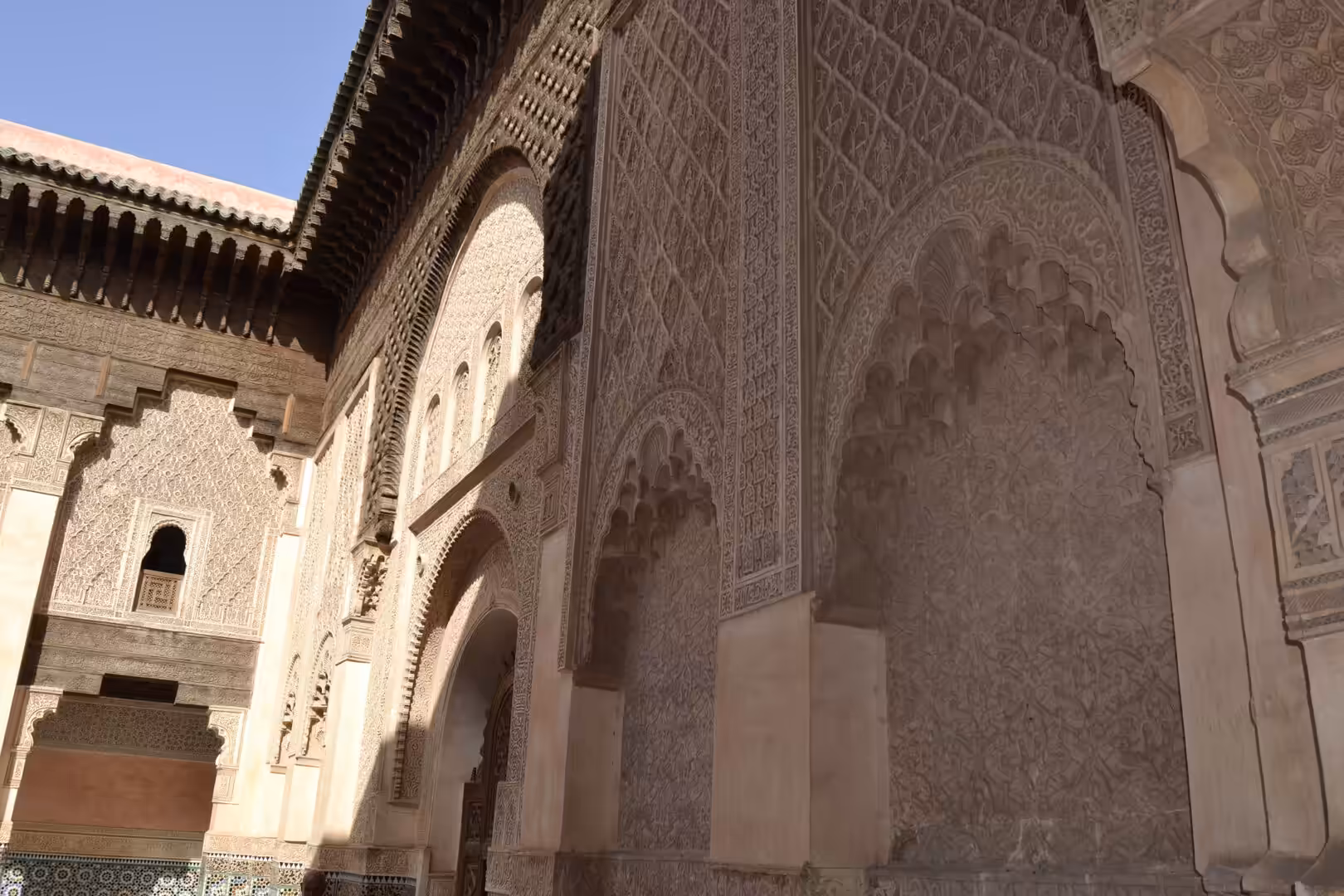 Sunlit courtyard wall with carved arches at Ben Youssef Madrasa
