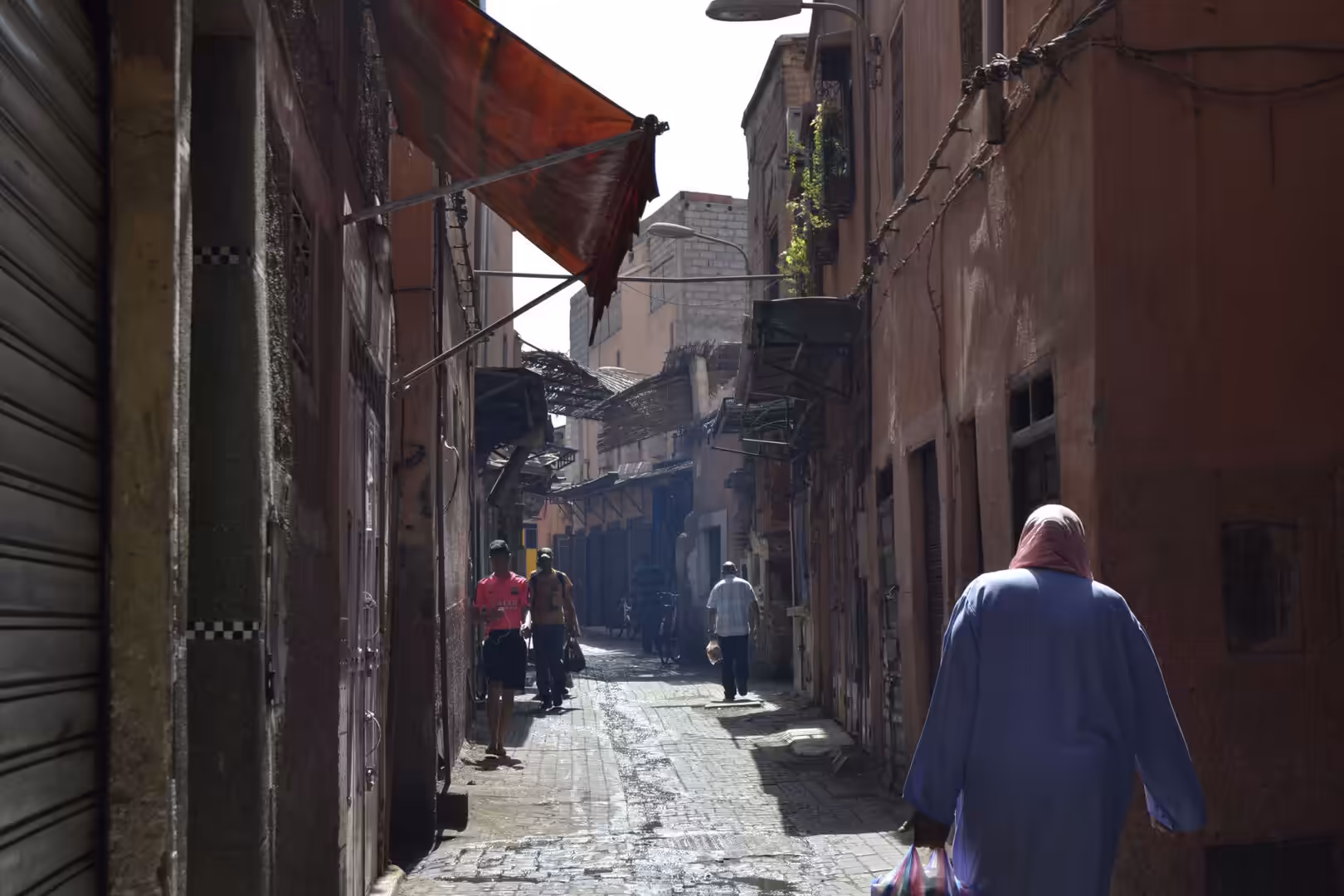 Pedestrians walking along a narrow alley in the Medina of Marrakech