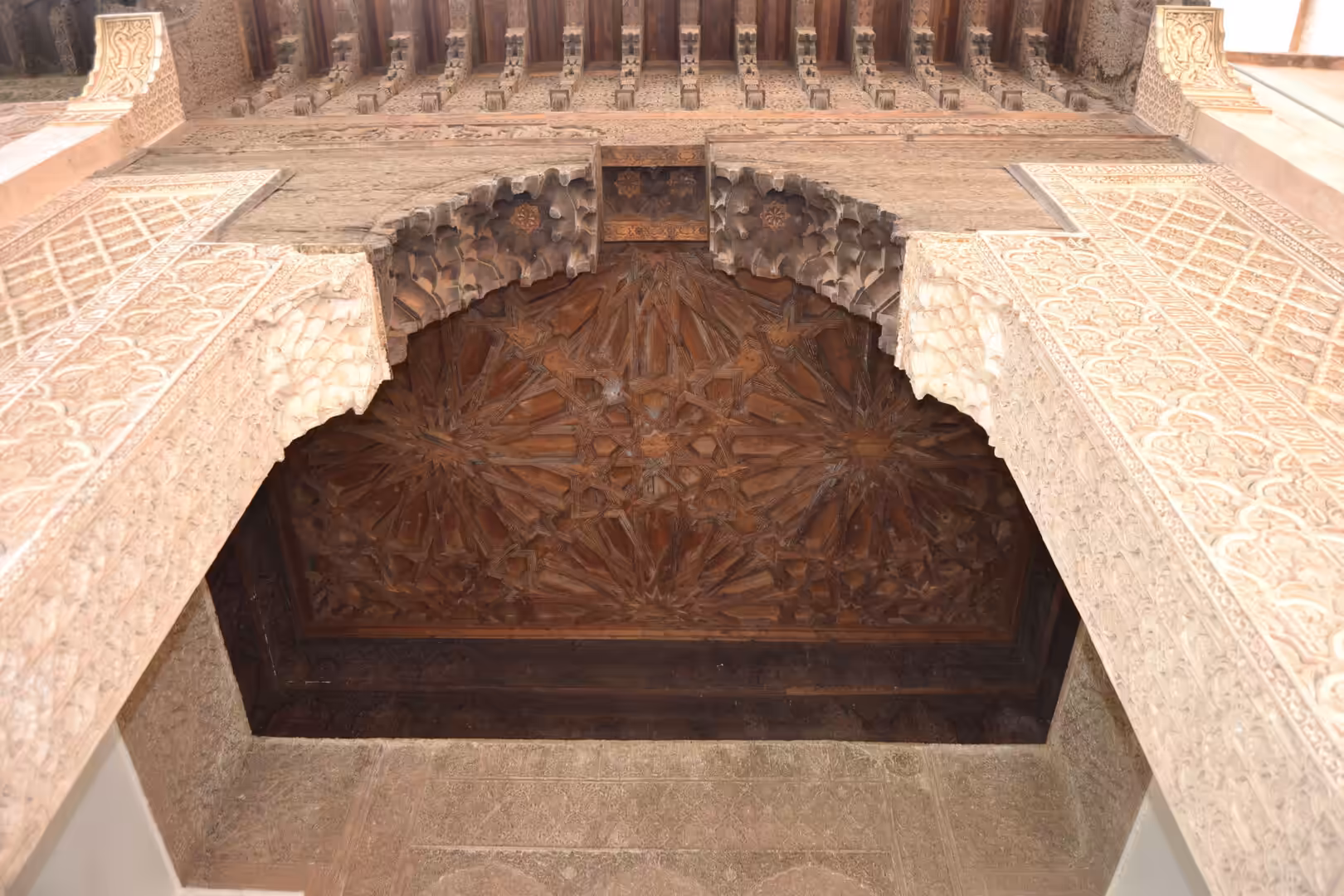 Carved wooden ceiling and stucco arch in a historic building in Marrakech