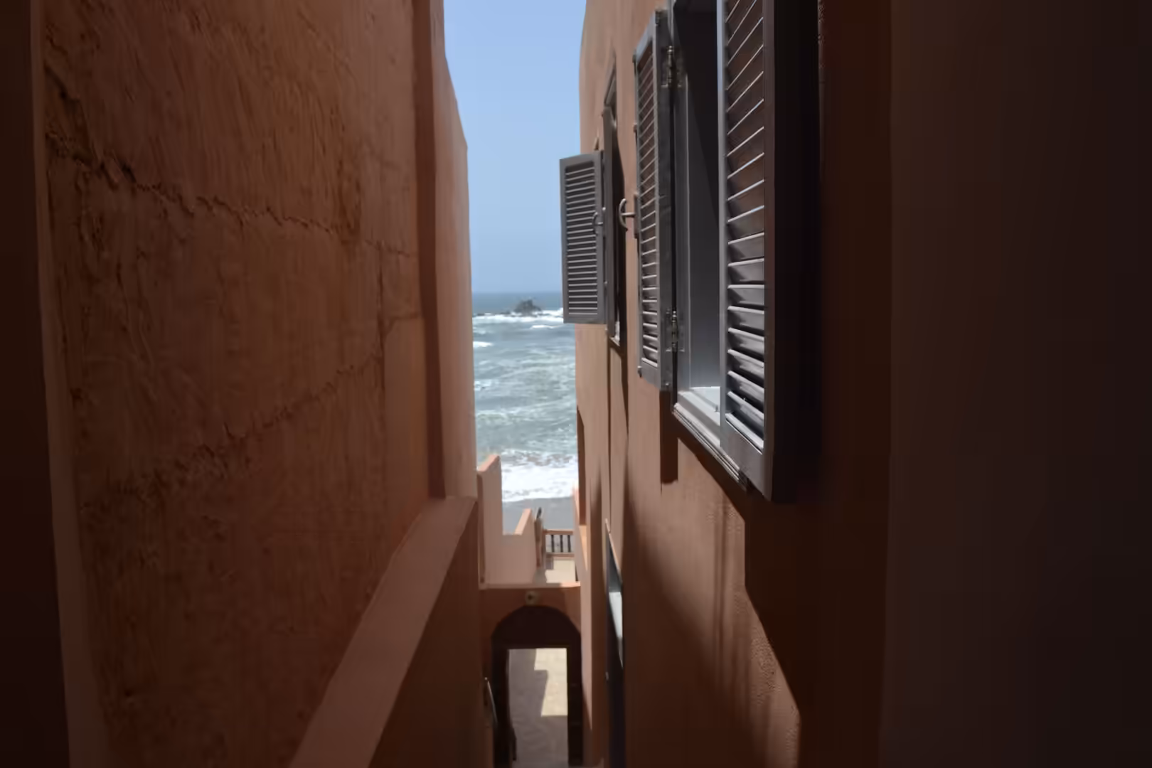 Narrow passage between coastal buildings with ocean view at Legzira Beach