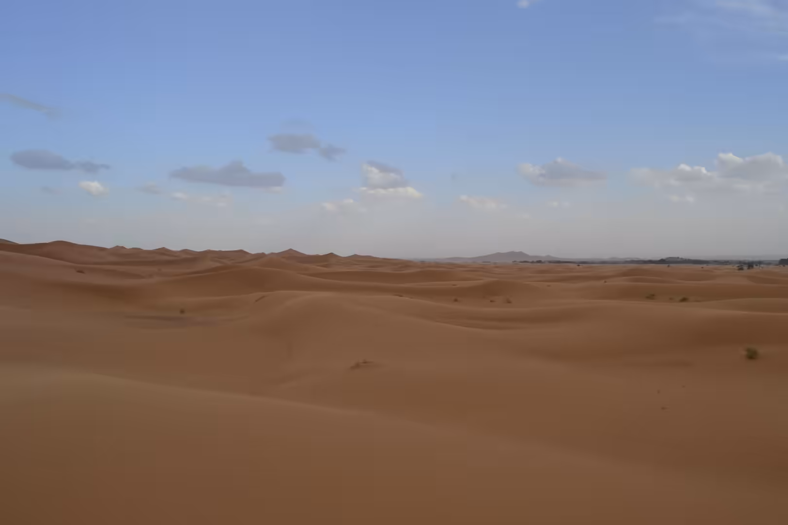 Vast Sahara sand dunes under blue sky