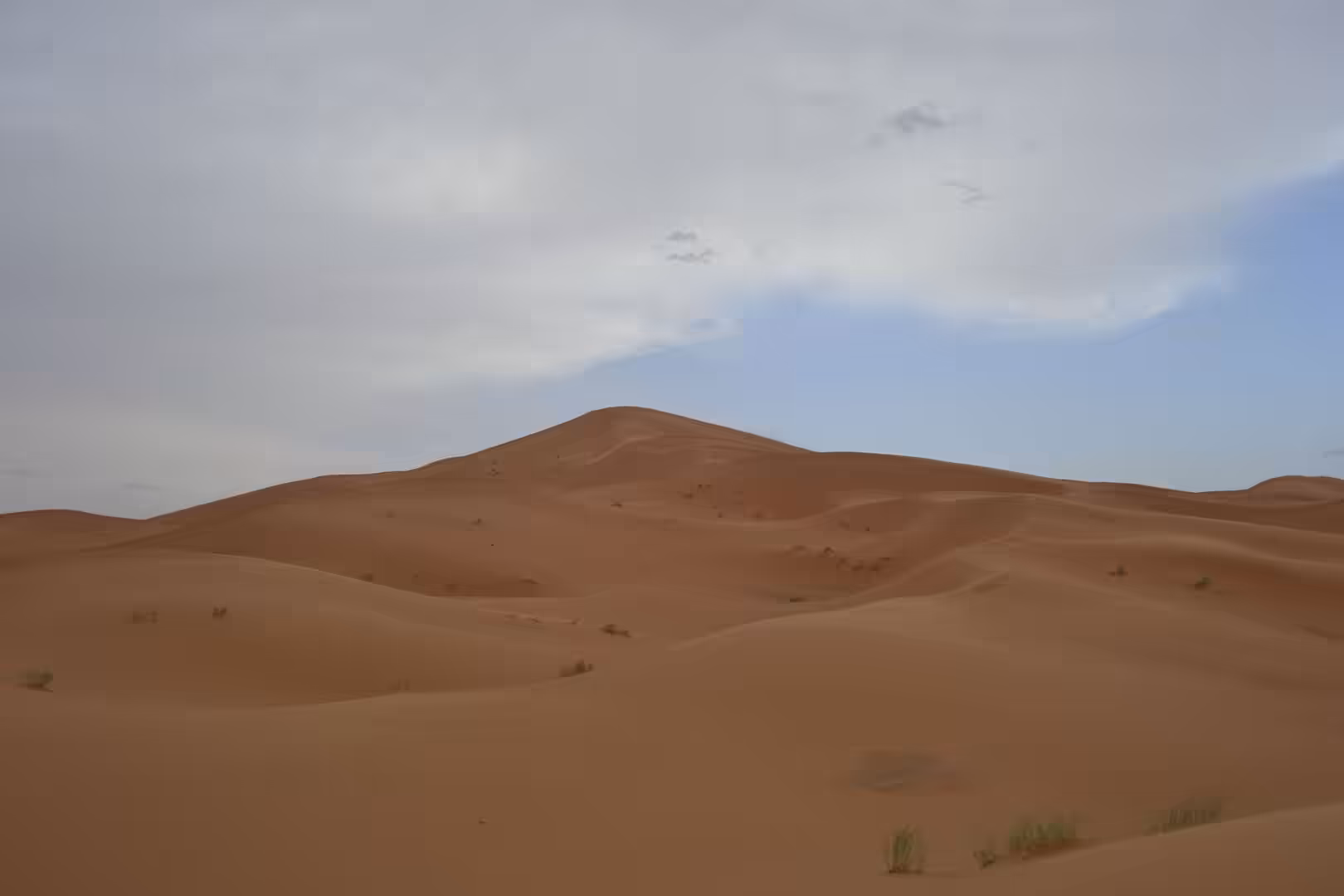 Large Sahara sand dune under cloudy sky