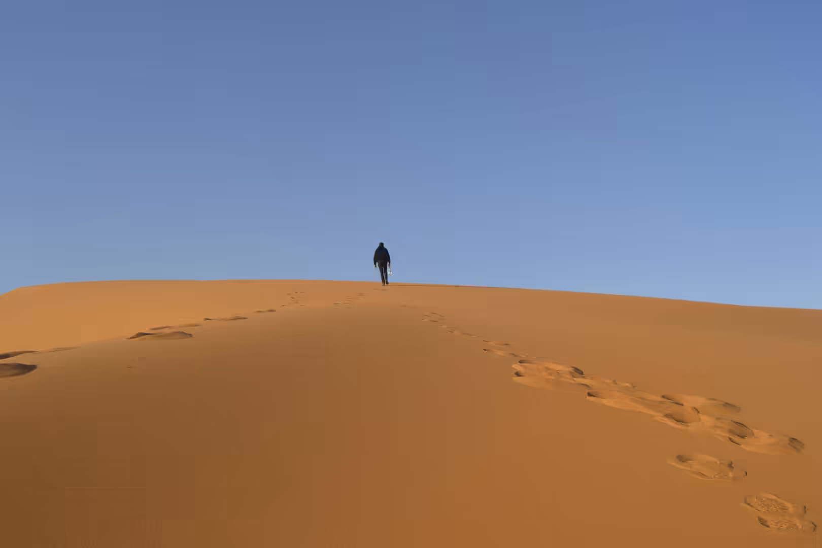 Person walking along ridge of Sahara sand dune