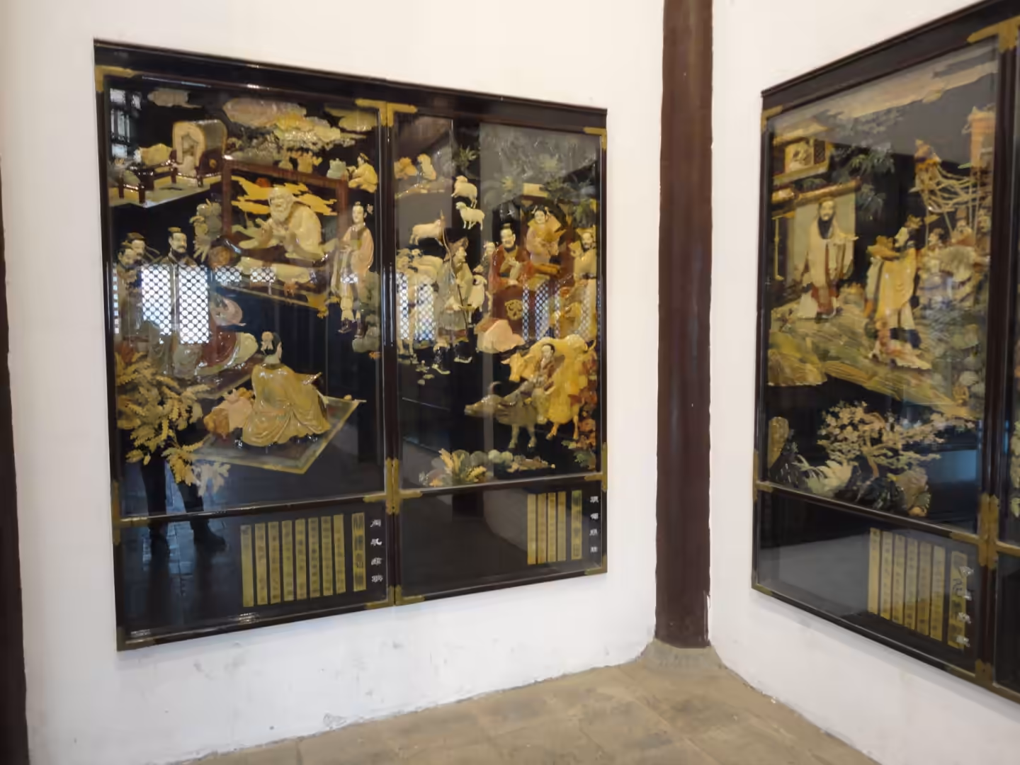 Decorated Chinese lacquer screen panels with carved figures and scenes inside a temple hall