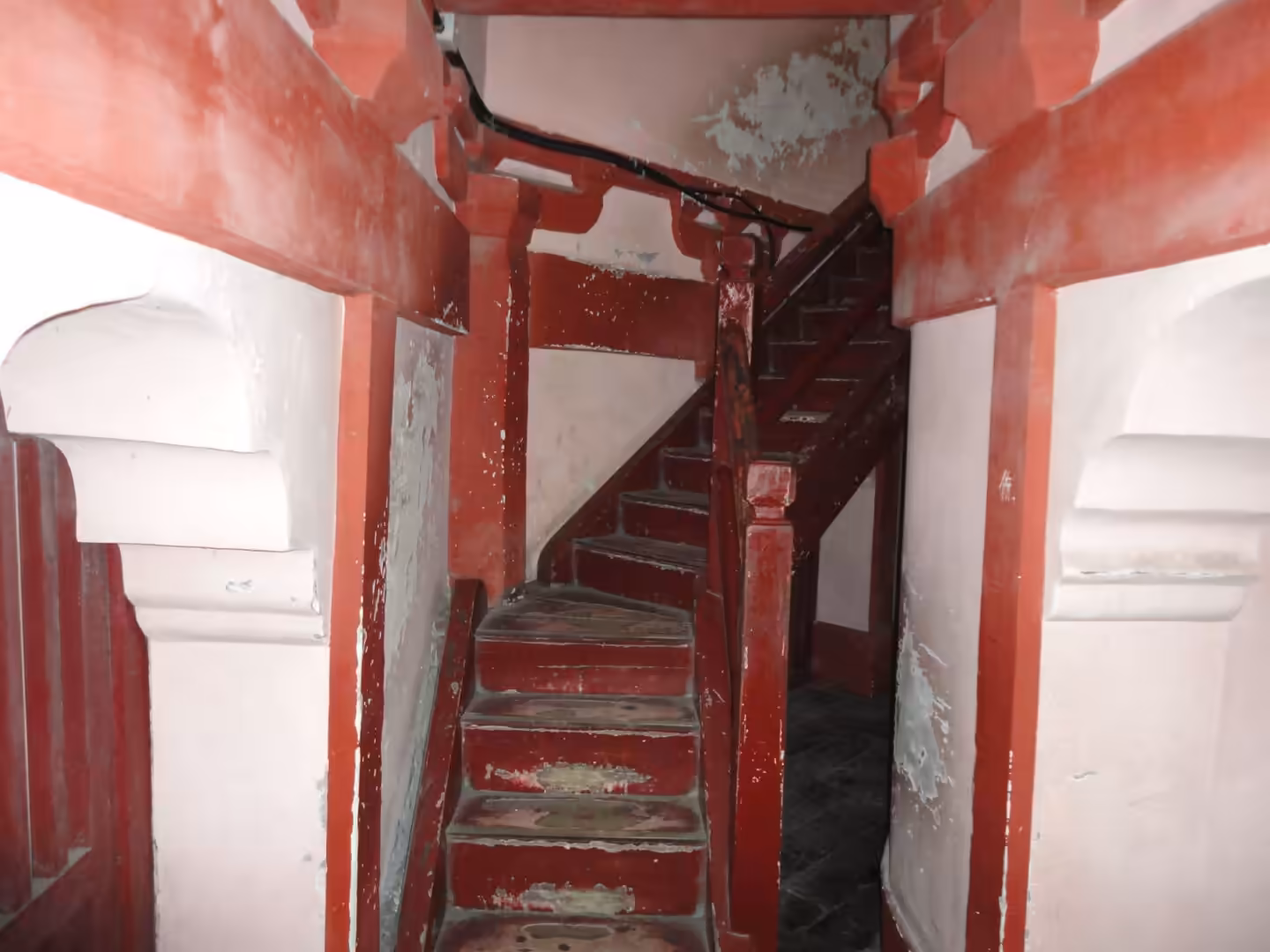 Narrow red wooden staircase inside a traditional Chinese pagoda