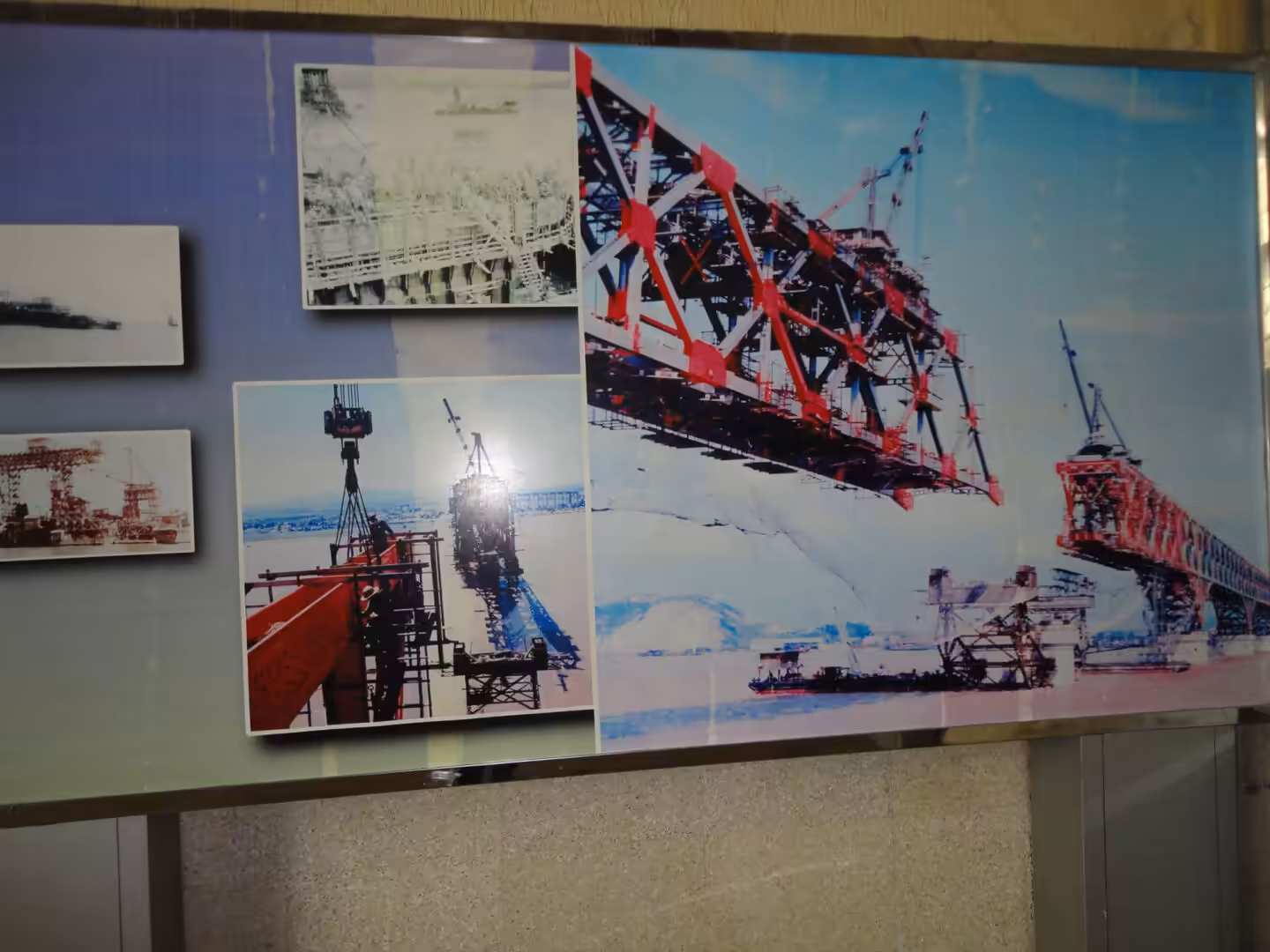 Museum display panel showing historical photographs of the Nanjing Yangtze River Bridge under construction, with steel trusses being lifted into place over the river