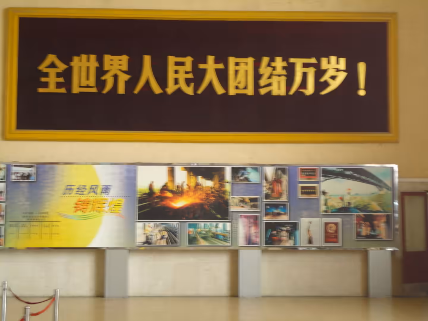 Large Chinese slogan above a museum exhibition with historical photos of bridge construction and engineering scenes