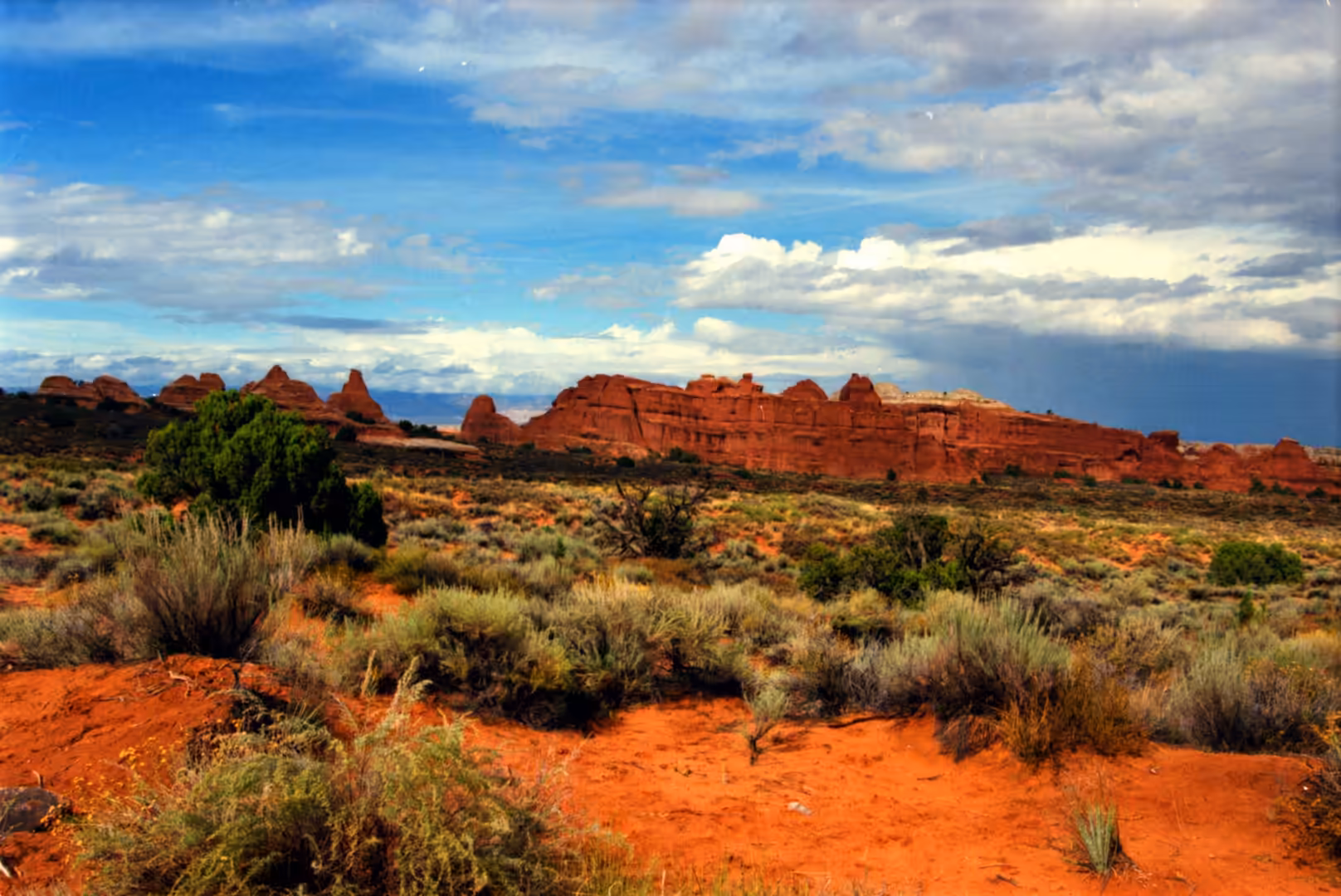 Red sandstone buttes across a desert plain with shrubs