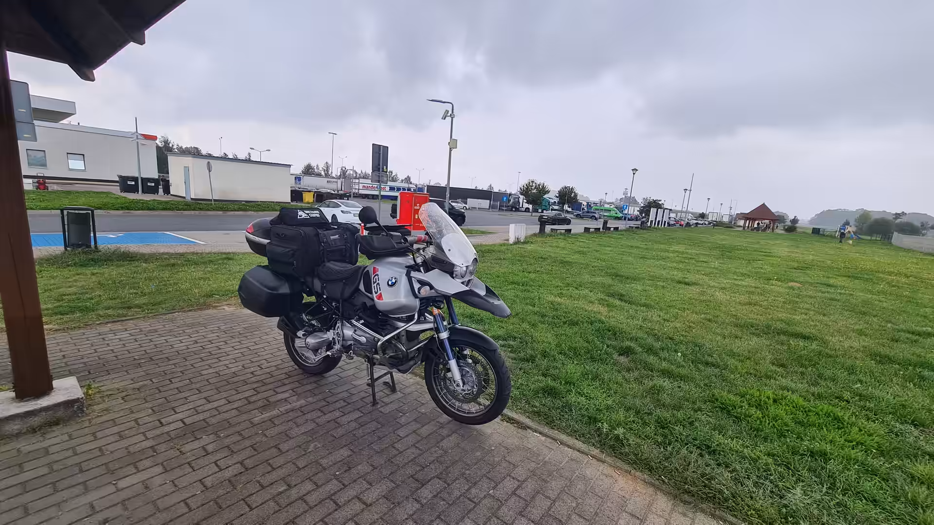 Fully loaded BMW R 1150 GS Adventure motorcycle parked at a roadside rest area under cloudy skies during a long-distance journey.