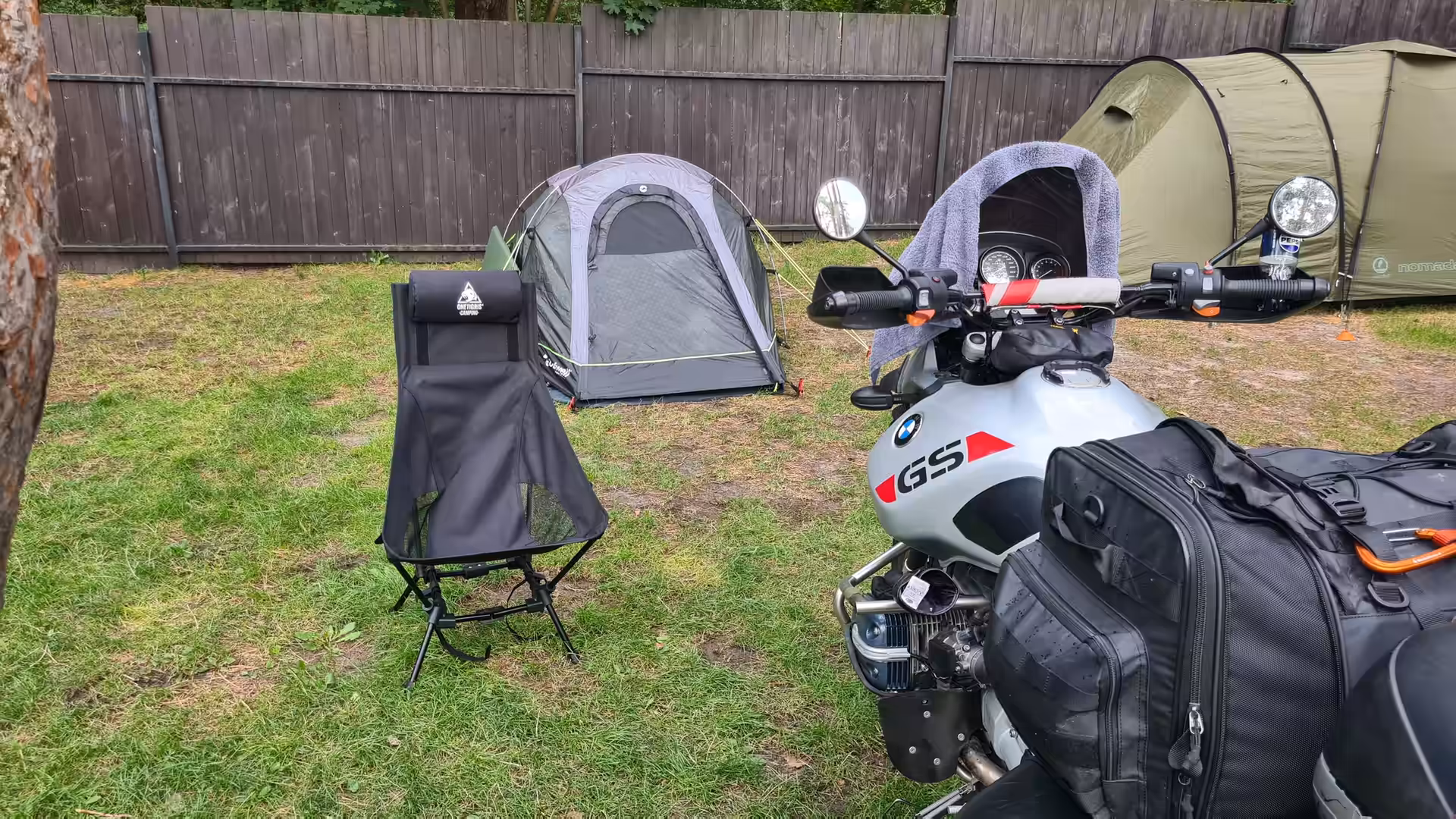 BMW R 1150 GS Adventure parked beside a tent at a campsite, fully loaded with touring luggage and camping equipment.