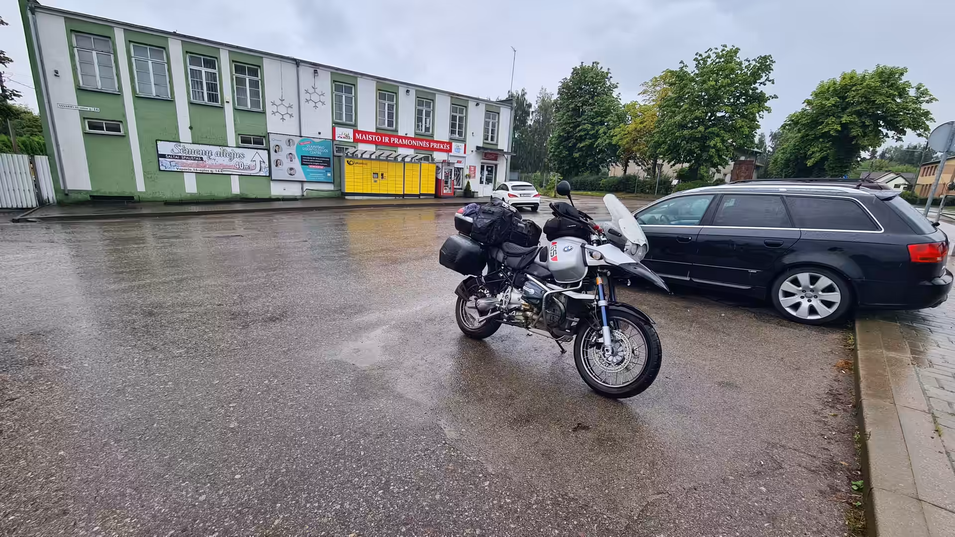 A fully loaded BMW GS Adventure parked on a wet street after rainfall in a small town in Lithuania.