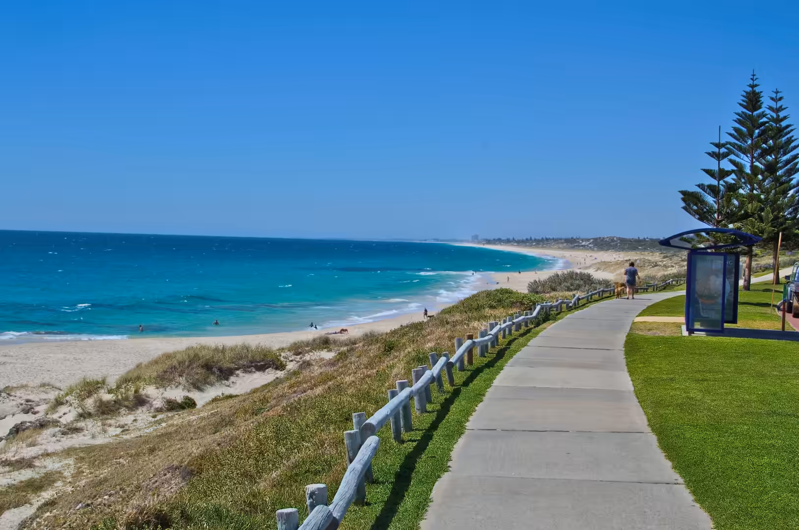 A timber-posted path runs beside a turquoise bay and white beach.