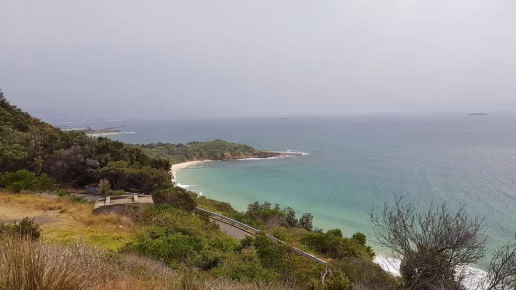 A bright turquoise bay curves into a sandy cove beneath a forested ridge.