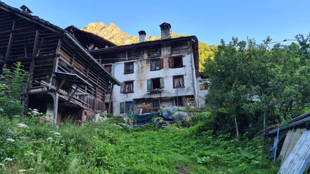 Traditional timber houses bask in sunlight beneath a glowing rocky peak.