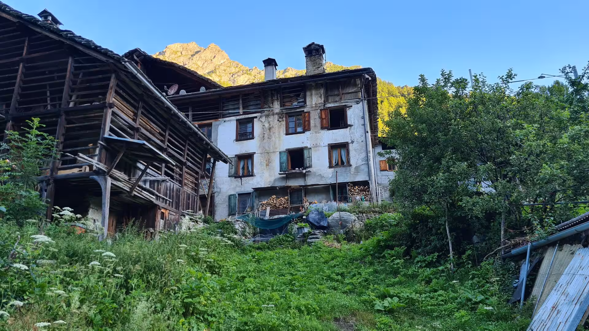Traditional timber houses bask in sunlight beneath a glowing rocky peak.