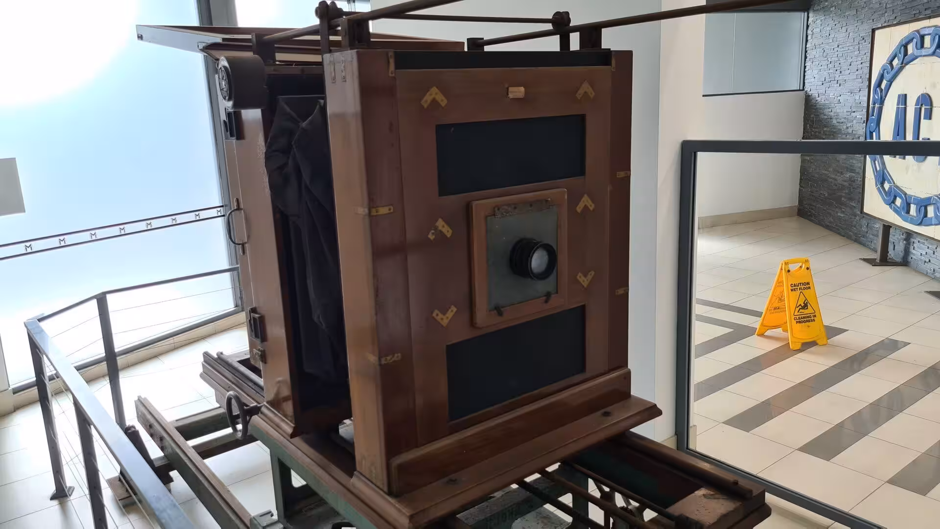 A grand old wooden bellows camera is displayed on a rail-and-cart stand.