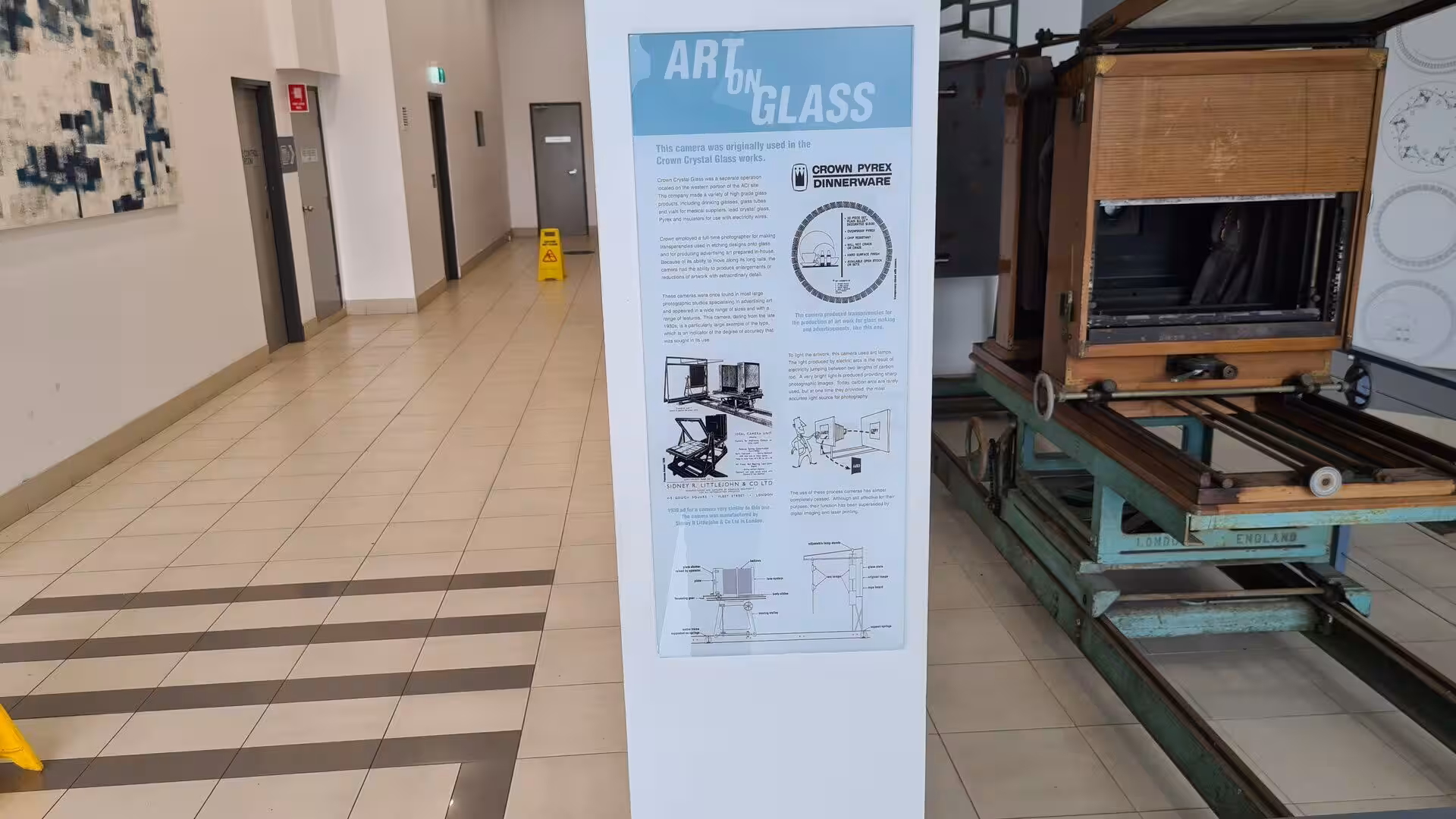An information board titled Art on Glass describes a vintage camera beside it.