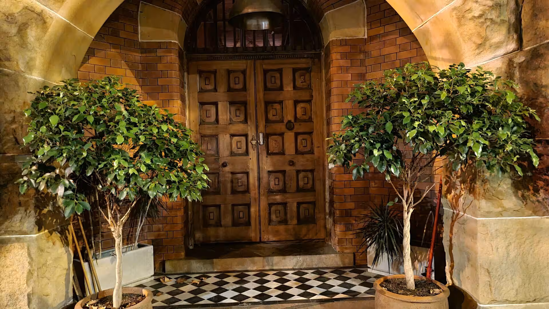 Pair of carved wooden double doors set beneath a warm brick arch