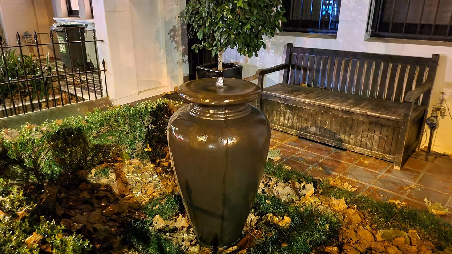 Large ceramic jar beside a wooden bench in a night garden